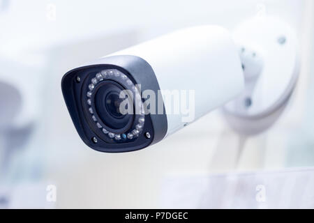 Big white professional surveillance camera. CCTV mounted on ceiling. LED IR lights around lens. Security system concept. Copyspace, neutral light blue Stock Photo