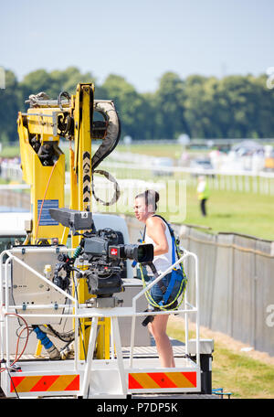 Skilled, single camerawoman filming live event at Worcester Racecourse on a hot, sunny afternoon in July, the day of Princess Anne's royal visit. Stock Photo