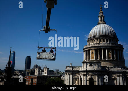 Window cleaners are suspended in a cradle above an office block next to St Paul's Cathedral, in Central London, Britain July 3, 2018. Stock Photo