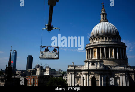 Window cleaners are suspended in a cradle above an office block next to St Paul's Cathedral, in Central London, Britain July 3, 2018. Stock Photo