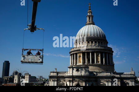 Window cleaners are suspended in a cradle above an office block next to St Paul's Cathedral, in Central London, Britain July 3, 2018. Stock Photo