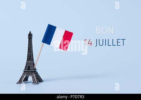 a miniature of the Eiffel Tower, a french flag and the text bon 14 juillet, happy 14 july, the national day of France written in French, against a pal Stock Photo