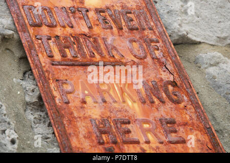 “Don’t even think of parking here”. Humorous No Parking message on a rusty textured old metal sign. Isle of Portland, Dorset, England, United Kingdom. Stock Photo