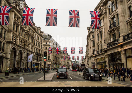 LONDON, UK - APRIL 2018: Red buses and taxis passing under union Jack flags before Royal wedding in Regent street. Stock Photo