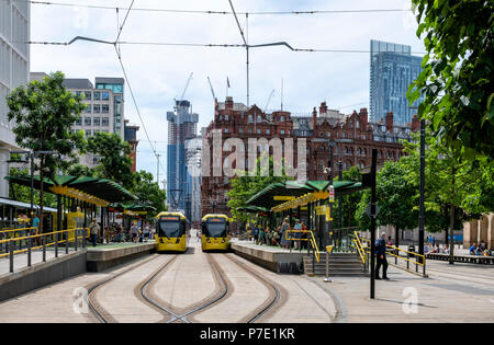 Two modern yellow Metrolink trams stop at St Peters Square Station in the centre of Manchester Stock Photo