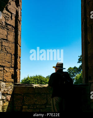 Framed silhouette of man wearing Panama hat in ruined window frame with blue sky, Linlithgow Palace, West Lothian, Scotland, UK