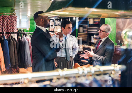 Tailors and customer having discussion in traditional tailors shop Stock Photo