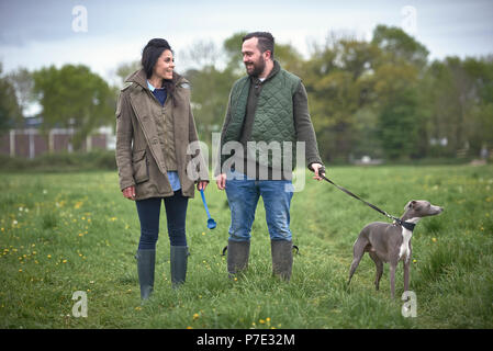 Woman and man walking dog in field