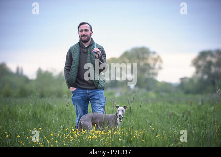 Young man with his dog in field, portrait