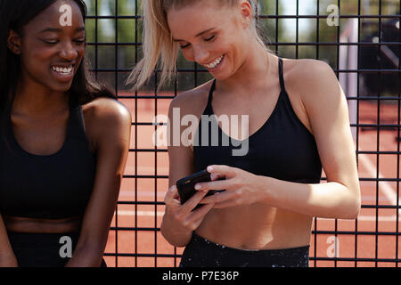Young women smiling, reading text on mobile phone Stock Photo