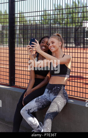 Young women smiling, reading text on mobile phone Stock Photo