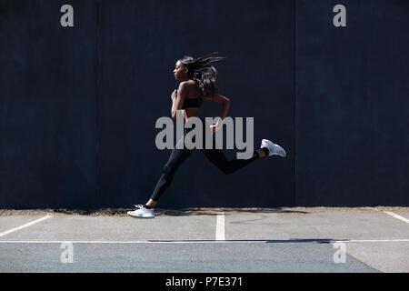 Young woman running on sports court Stock Photo
