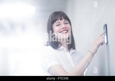 Woman using wall mounted touch screen control panel Stock Photo