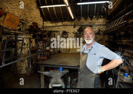 Blacksmith with hands on hips in blacksmiths shop, portrait Stock Photo