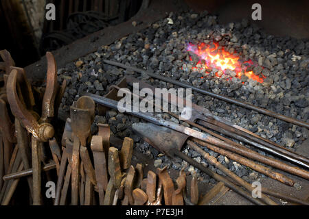 Blacksmiths tongs and tools by forge fire in blacksmiths shop Stock Photo