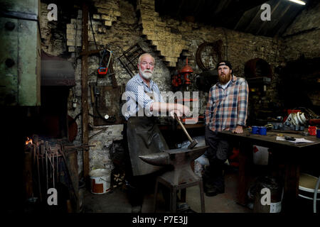 Senior blacksmith and son in blacksmiths shop, portrait Stock Photo