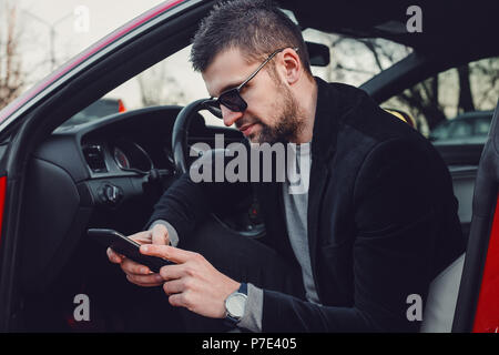 Bearded businessman using mobile phone in luxury car Stock Photo