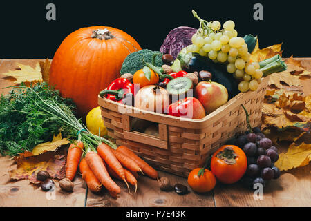 Assortment of fresh and ripe autumn vegetables and fruits on a rustic wooden table with black background Stock Photo