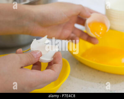 Hands break the raw egg. Separation of egg white from yolk Stock Photo