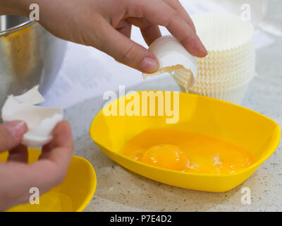 Hands break the raw egg. Separation of egg white from yolk Stock Photo