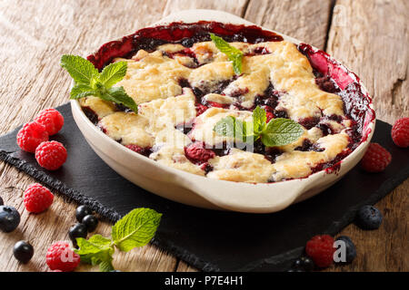 Pie sweet cobbler of raspberries, currants and blueberries close-up in a dish for baking on a table. horizontal Stock Photo