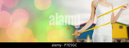 Woman measuring weight with measuring tape on waist near Summer beach huts with transition Stock Photo