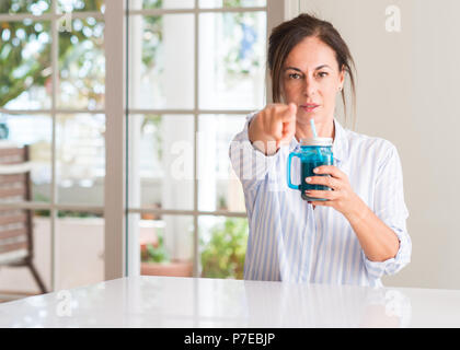 Middle aged woman drinking milk shake in a glass pointing with finger to the camera and to you, hand sign, positive and confident gesture from the fro Stock Photo