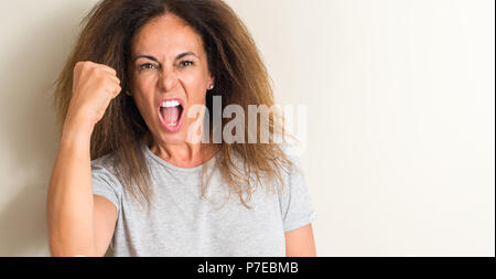 Curled hair brazilian woman annoyed and frustrated shouting with anger, crazy and yelling with raised hand, anger concept Stock Photo