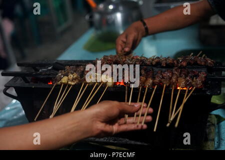 Food Vendor Grilling Meat Satay with charcoal at Street Food Market Stock Photo