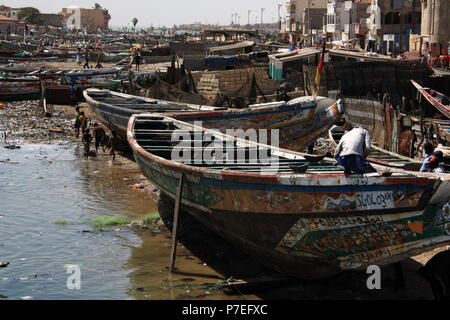 Kids playing among colorful painted pirogues in the fisherman's wharf of Saint-Louis-du-Sénégal, Senegal Stock Photo