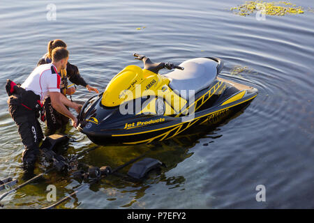 29 June 2018 a young couple in wet gear pushing a powerful Yamaha Jet-Ski off its trailer into the sea at Groomsport Harbour Northern Ireland Stock Photo
