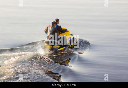 29 June 2018 A young couple on board a powerful Yamaha Jet-Ski as they head to sea from Groomsport Harbour Northern Ireland on a flat calm evening Stock Photo