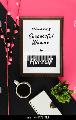 Wood frame with motivational and inspirational wisdom quote on pink and black background. Behind every successful woman is herself. Stock Photo