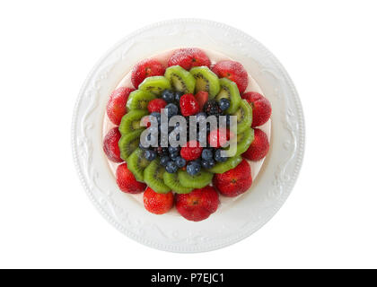 Fresh fruit on a shortbread cake with whipped cream topping on off white porcelain plate isolated on white. Flat lay, top view. Stock Photo