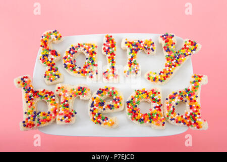 Fairy bread spelled with fairy bread on a white rectangular plate on pink background. Fairy bread is commonly served at children's parties in Australi Stock Photo