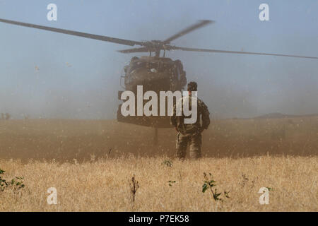 A Green Beret from 10th Special Forces Group (Airborne) stands by as a UH-60 lands near Chatfield Reservoir, outside of Littleton, Colo., June 28, 2018. Soldiers from 10th Special Forces Group honed their ability to perform static-line jumps and helo-cast into the reservoir, thereby sharpening the unit’s ability to operate on land, sea, and air. Stock Photo