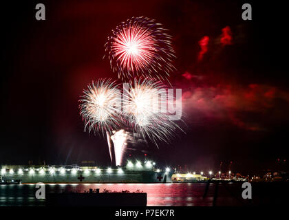 180704-N-HK946-1044 PEARL HARBOR (July 4, 2018) Fireworks shoot over Military Sealift Command (MSC) hospital ship USNS Mercy (T-AH 19) at Joint Base Pearl Harbor-Hickam during Rim of the Pacific (RIMPAC) exercise. Twenty-five nations, 46 ships, five submarines, about 200 aircraft and 25,000 personnel are participating in RIMPAC from June 27 to Aug. 2 in and around the Hawaiian Islands and Southern California. The world’s largest international maritime exercise, RIMPAC provides a unique training opportunity while fostering and sustaining cooperative relationships among participants critical to  Stock Photo