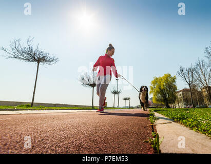 Young pretty girl running outdoor in the spring with her Bernese Mountain dog Stock Photo