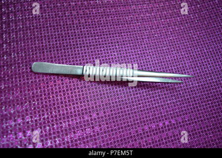 Steel pincer for working on a pink reflective background. Stock Photo