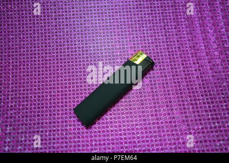 Matte black lighter lies on pink reflective background. Stock Photo