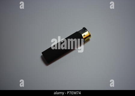 Matte black lighter lies on a white reflective background. Stock Photo