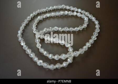Female gray plastic beads on a brown matte background. Stock Photo