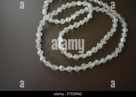 Female gray plastic beads on a brown matte background. Stock Photo