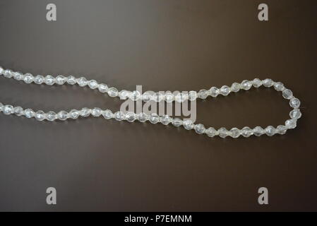 Female gray plastic beads on a brown matte background. Stock Photo