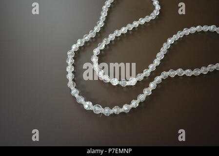 Female gray plastic beads on a brown matte background. Stock Photo