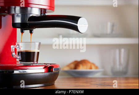 Making fresh coffee going out from a coffee espresso machine. Making espresso in glass transparent coffee cup. Stock Photo