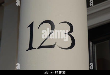 House number painted with black on white column by doorway in London, England. Number one hundred and twenty three, or one, two, three. 123. Stock Photo