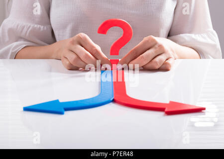 Blue And Red Arrows In Front Of Woman's Hand Showing Directions Stock Photo