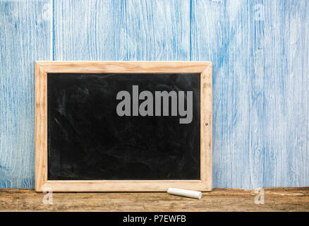 Blank chalkboard on rustic table, blue painted background Stock Photo