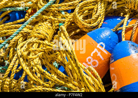 Crab pot fishing gear with yellow coiled polypropylene rope and buoys waiting to be launched into the ocean to catch seafood. Stock Photo